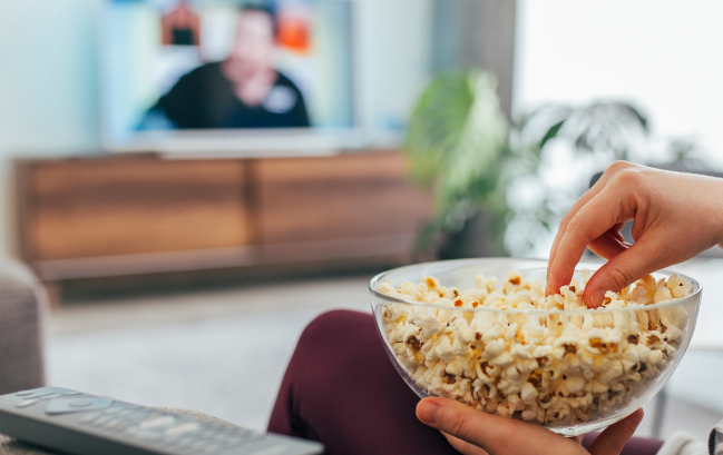 person watching tv with bowl of popcorn